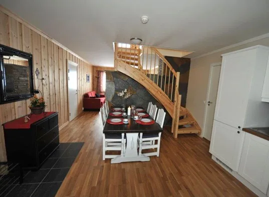 A dining area with a table beneath a wooden staircase.