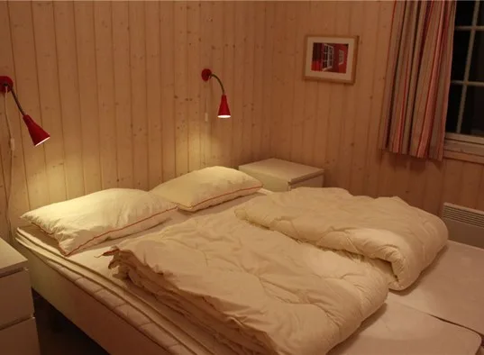 A bedroom with two beds dressed in light-colored bedding.