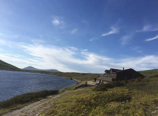 A lakeside landscape with a building on a grassy shoreline.