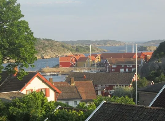 Un pueblo costero con casas de tejados rojos junto a una ensenada tranquila.