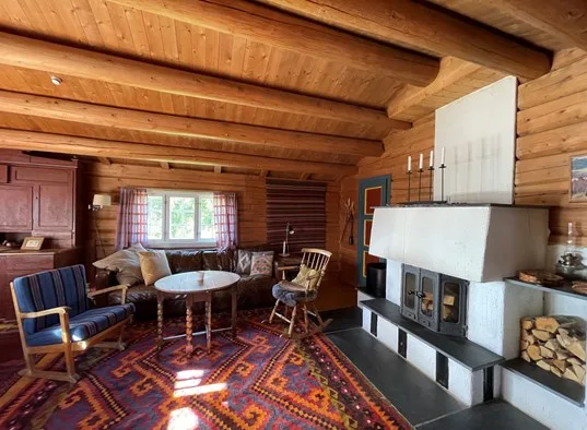 A timber-paneled living room with seating around a table and a large fireplace.