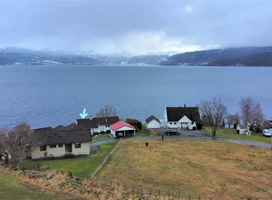 A lakeside scene with houses beside a grassy field.