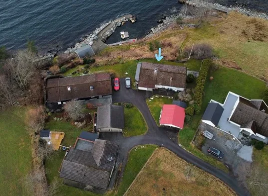 Aerial view of several buildings beside a shoreline and paved drive.
