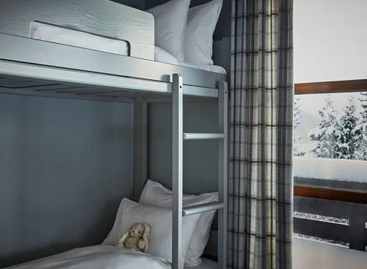 Zona para dormir con una litera y cortinas a cuadros junto a una ventana.