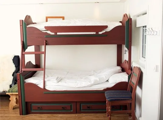 A bedroom with a wooden bunk bed and a chair beside it.