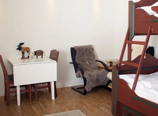 A bedroom with bunk beds, a rocking chair, and a small table.