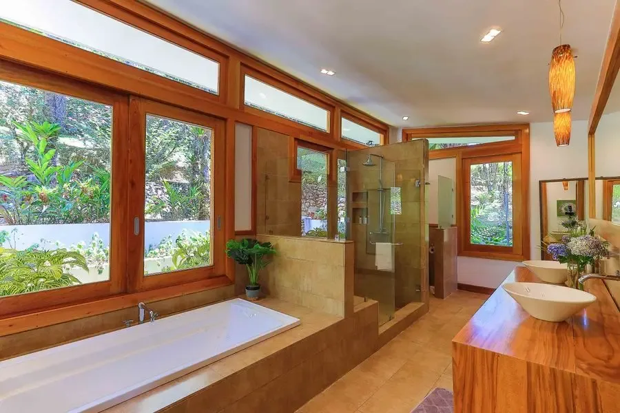 Un baño con bañera, ducha de vidrio y tocador de madera.