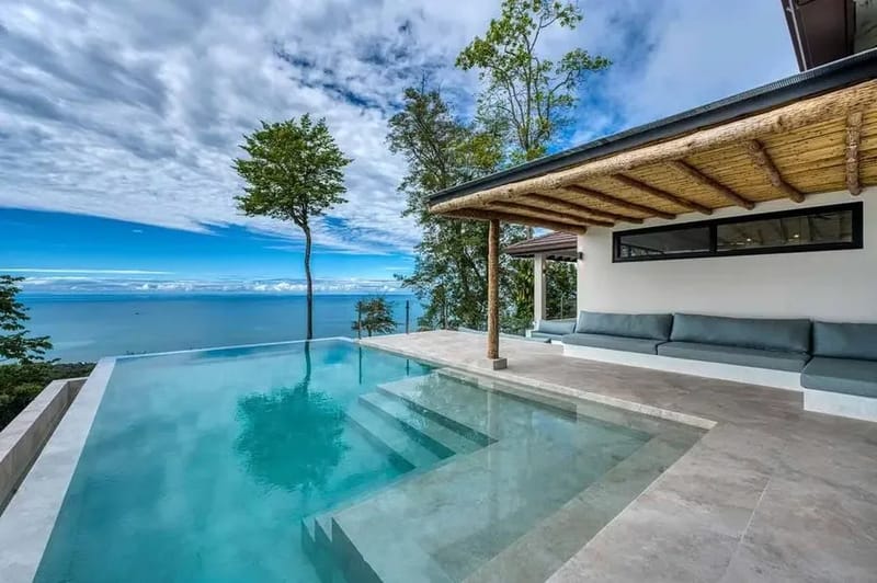 Piscina infinita junto al pabellón, con el océano en el horizonte