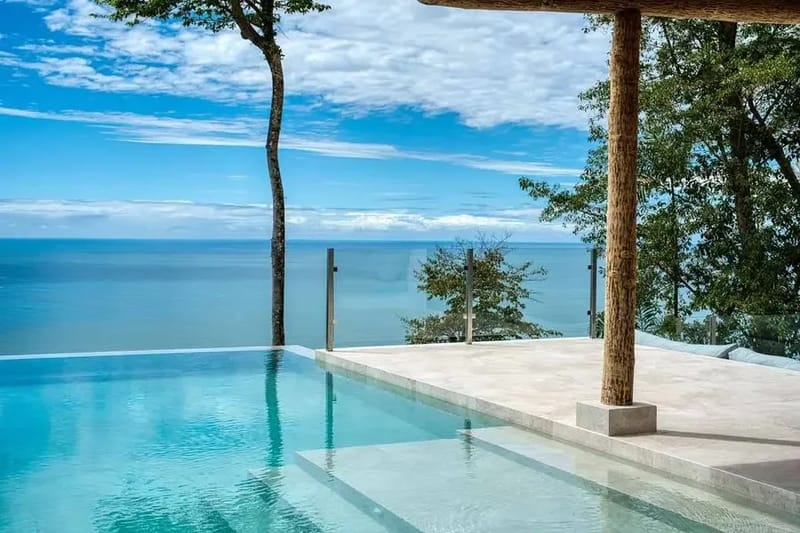 Piscina infinita bordeada de árboles, con el Pacífico ocupando el horizonte