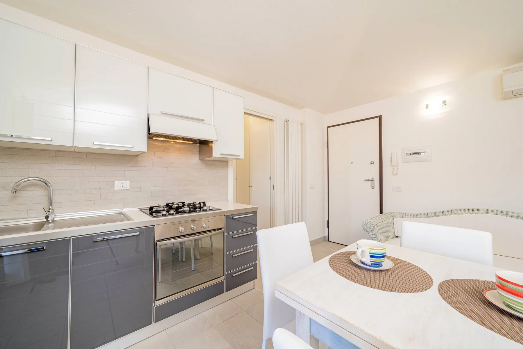 Una cocina y comedor luminosos con gabinetes, una estufa y una mesa puesta.