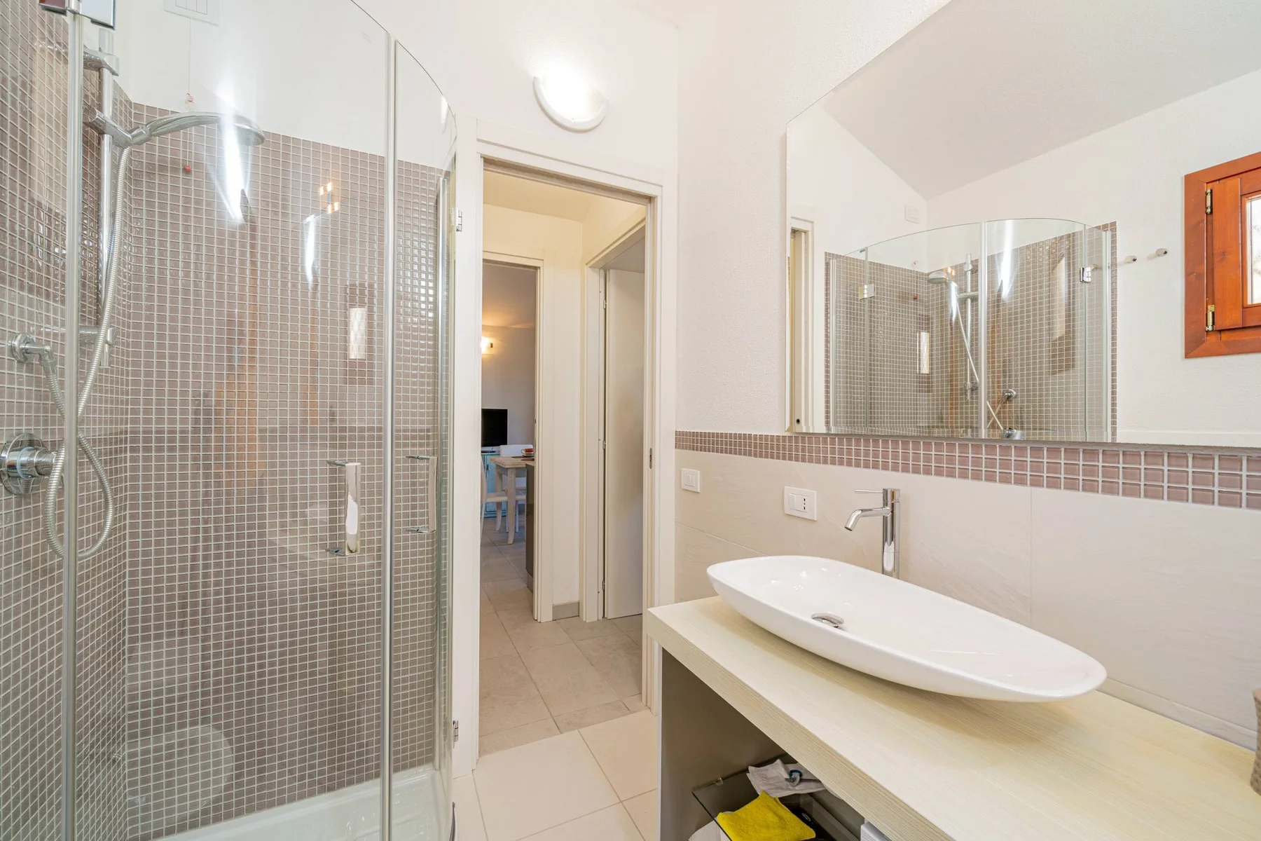 Un baño con una ducha de cristal, un lavabo y un espejo grande.