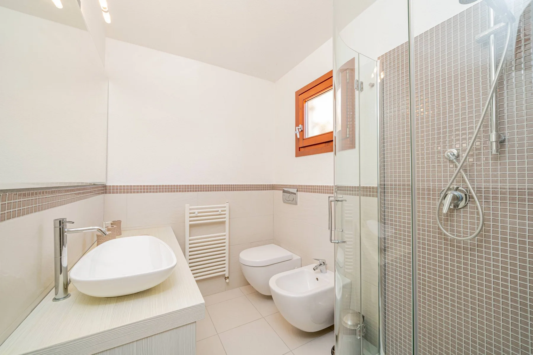 Un baño luminoso con bañera, inodoro, bidé y ducha de cristal.