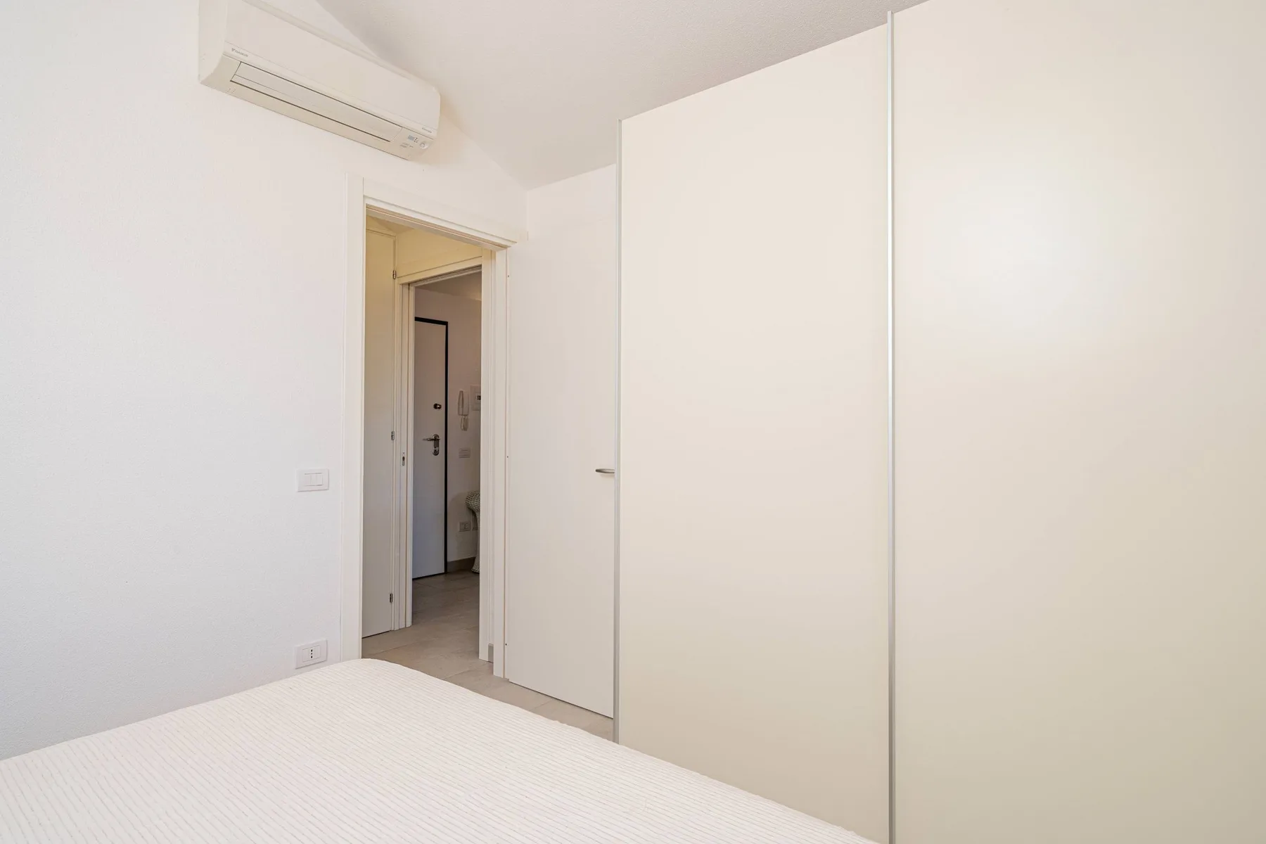 Un dormitorio luminoso con una cama, un armario grande y una puerta abierta.