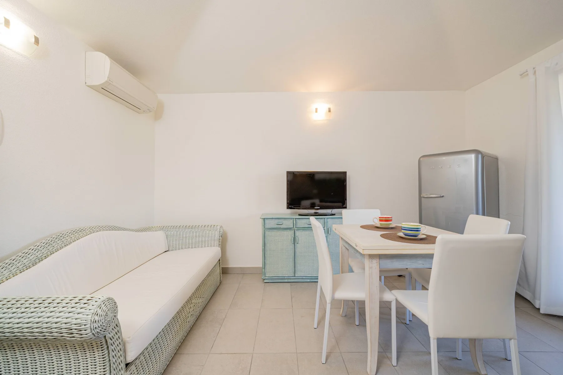 Una luminosa zona de comedor y estar con mesa, asientos y televisor.