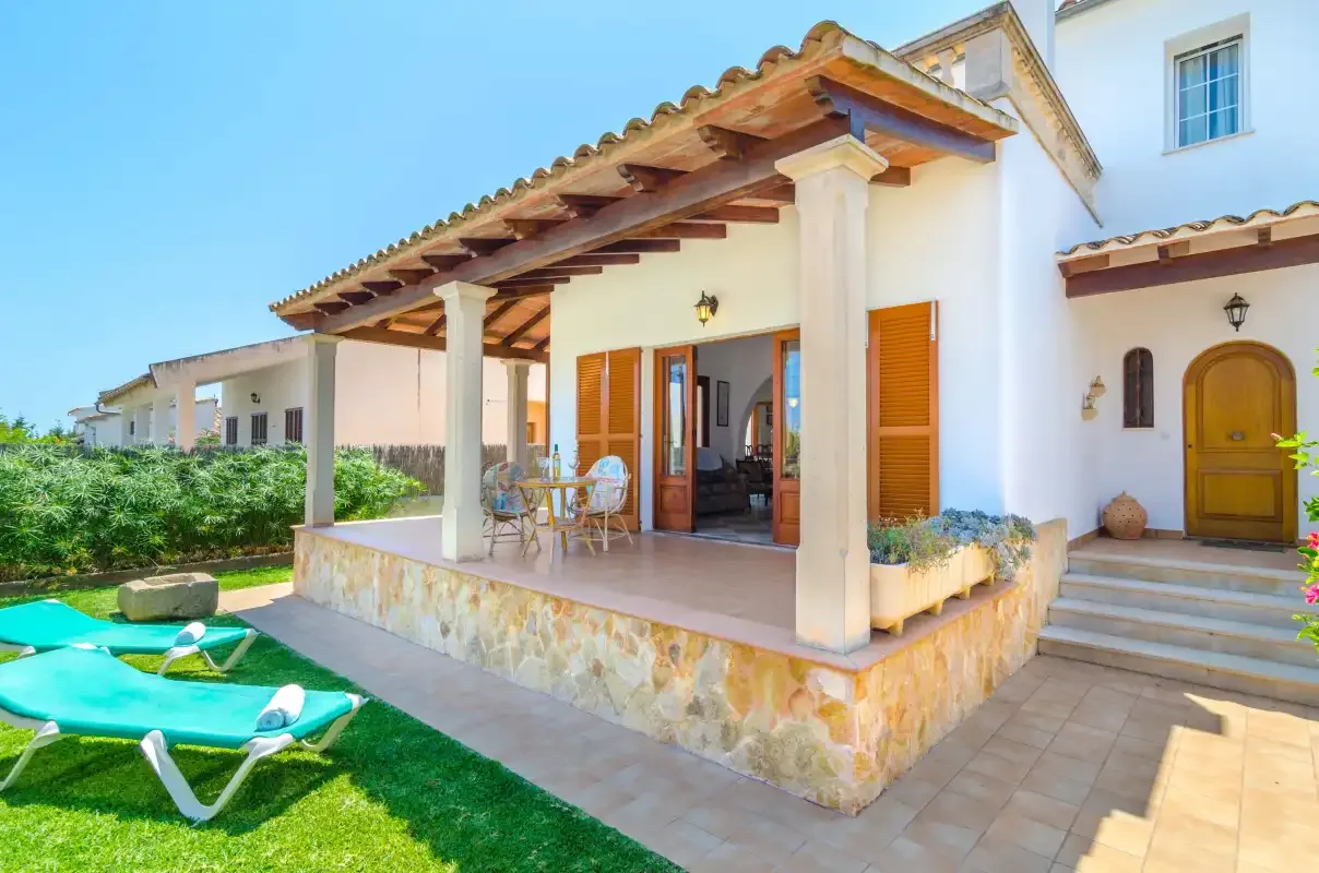 A house with a covered patio, outdoor seating, and a lawn.