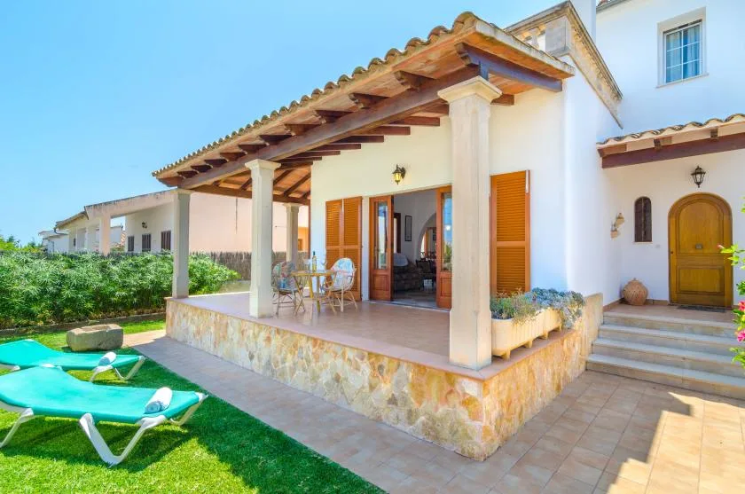 A house patio with a covered seating area, garden, and sun loungers.