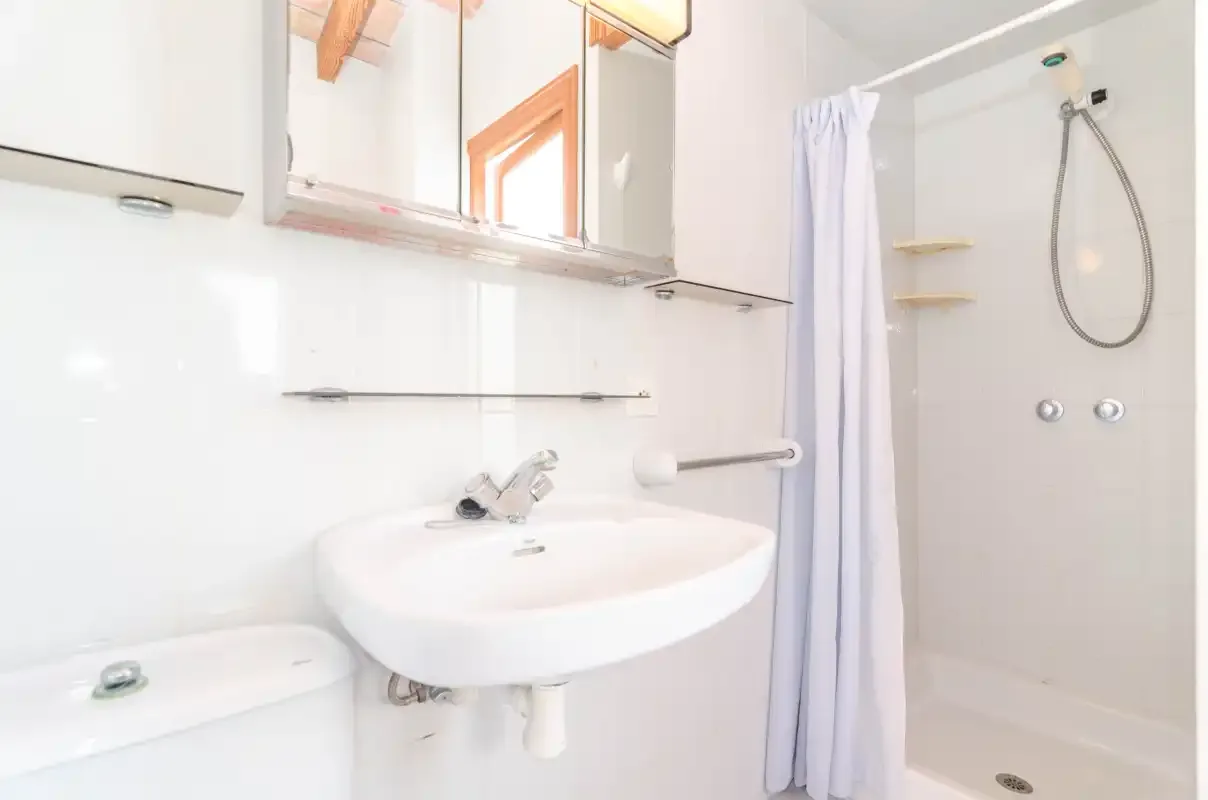 A bright bathroom with a sink and shower.