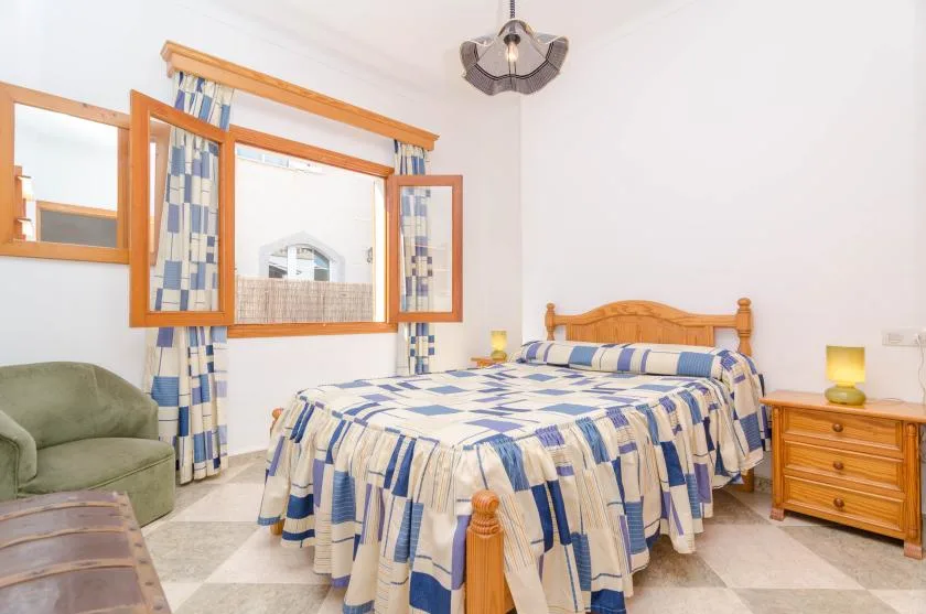 A bedroom with a wooden bed dressed in blue-and-white bedding and a window.
