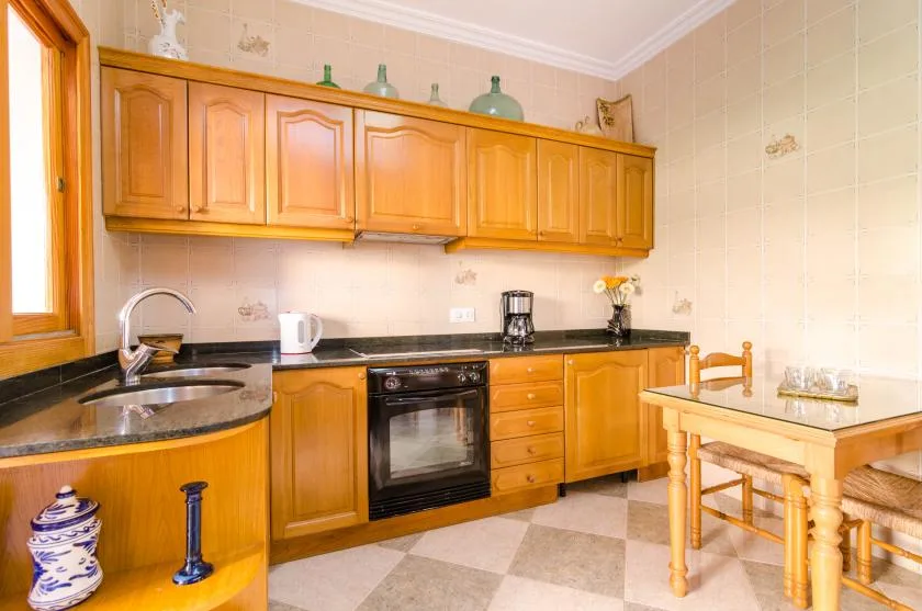 A kitchen with wooden cabinets, a countertop, and a small dining table.