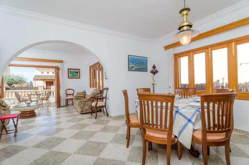 A dining area with wooden seating and large windows beside an arched opening to a patio.