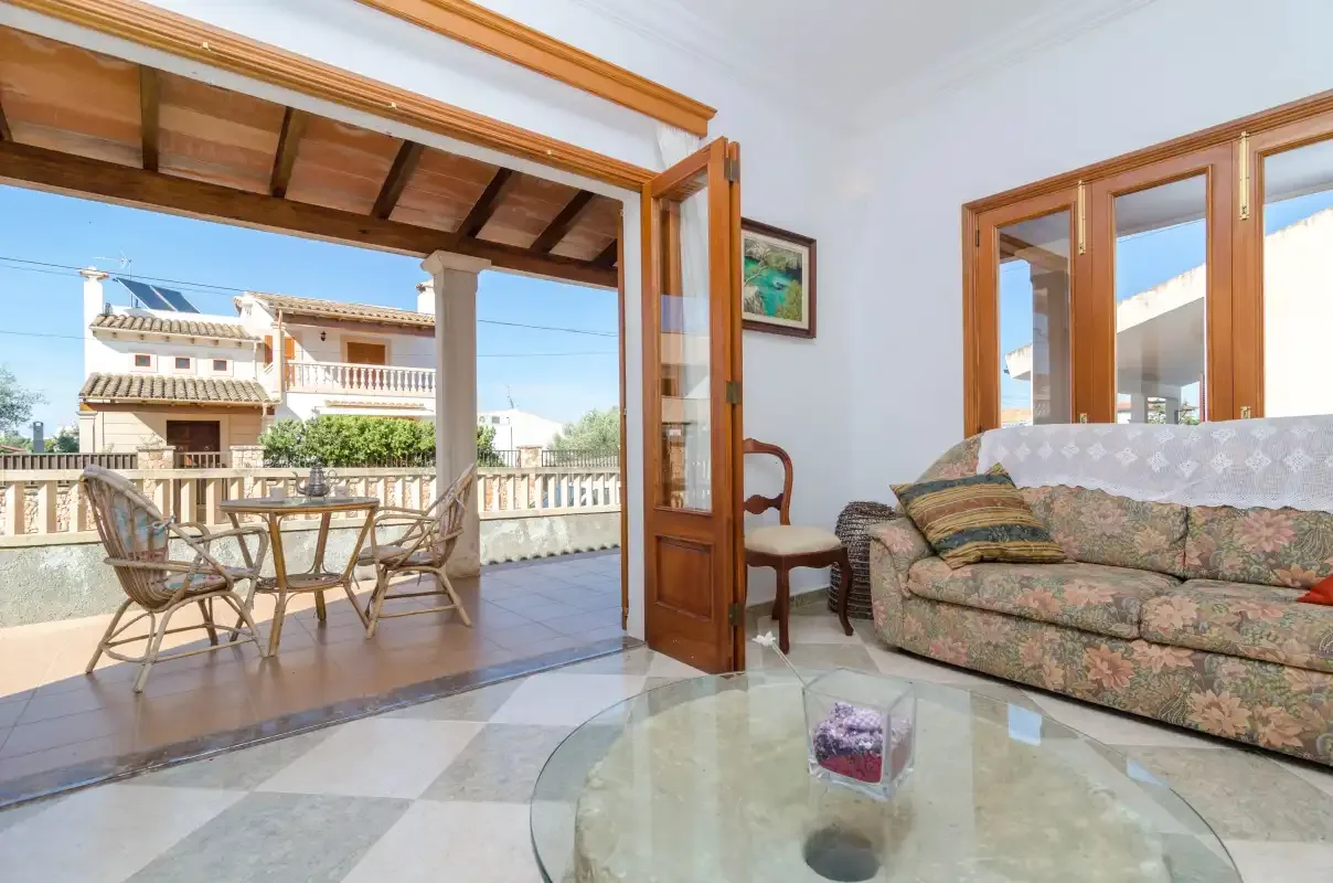 A living room opens onto a covered terrace with a table and seating.