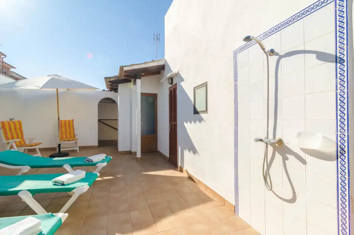 A sunny outdoor terrace with lounge seating and an outdoor shower.