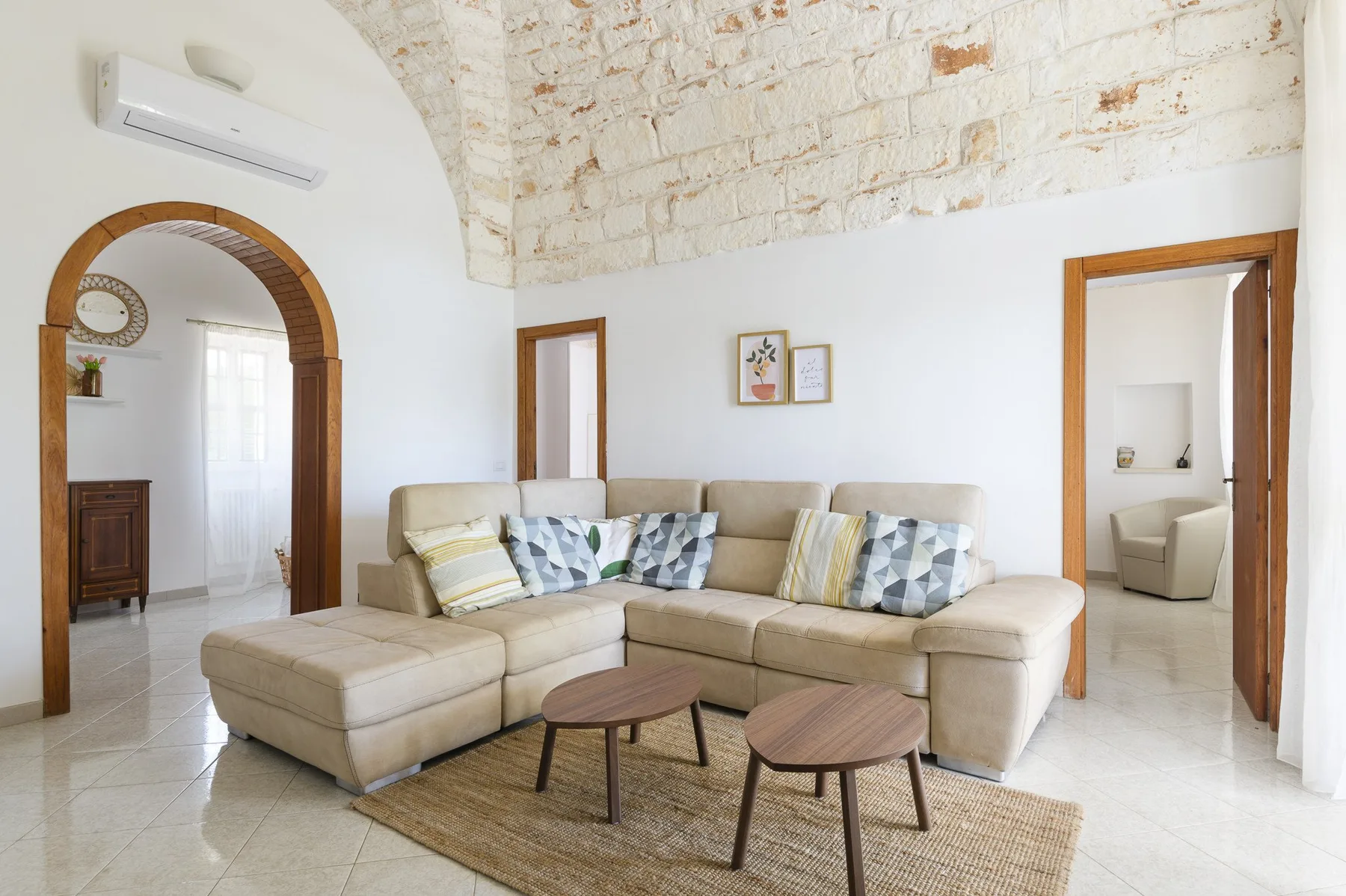 A bright living room with a sectional seating area and exposed brick ceiling.