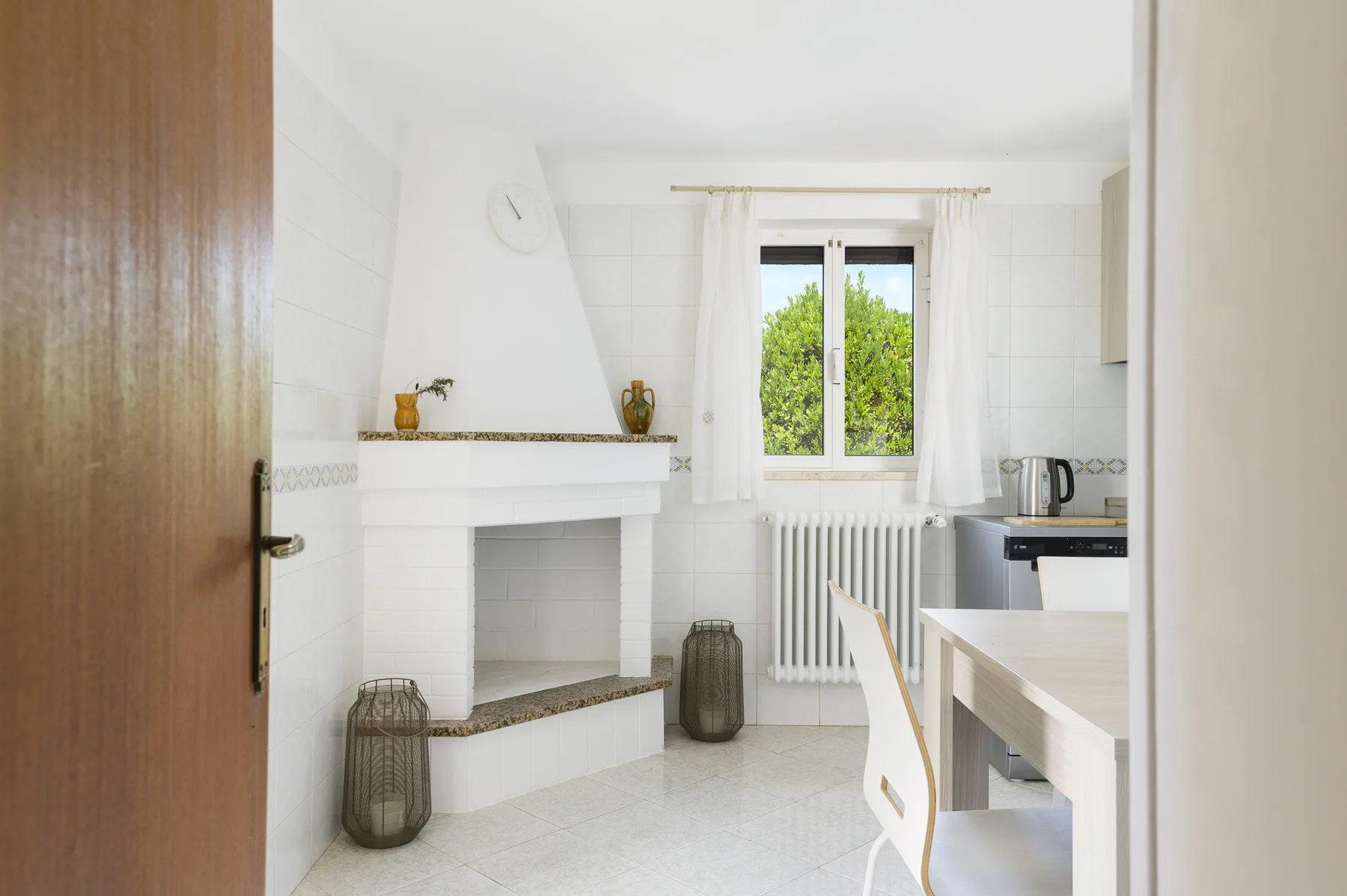 A bright kitchen with a tiled counter, a window, and a dining table.