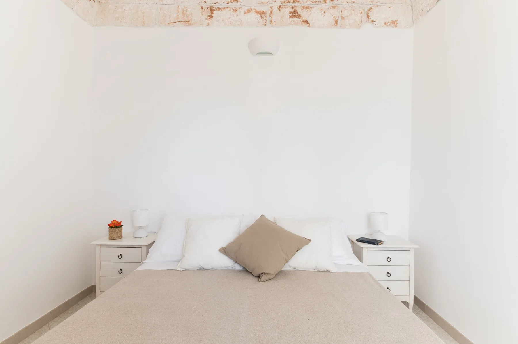 A bedroom with a neatly made bed and matching bedside tables.