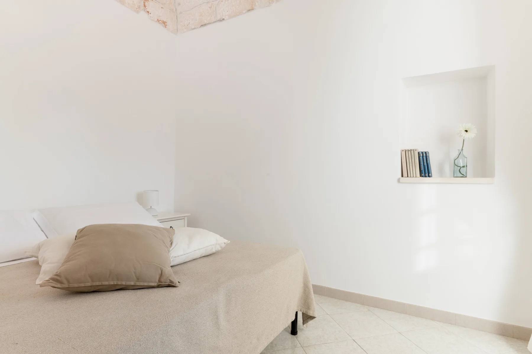 A simple bedroom with a bed and a recessed wall shelf.