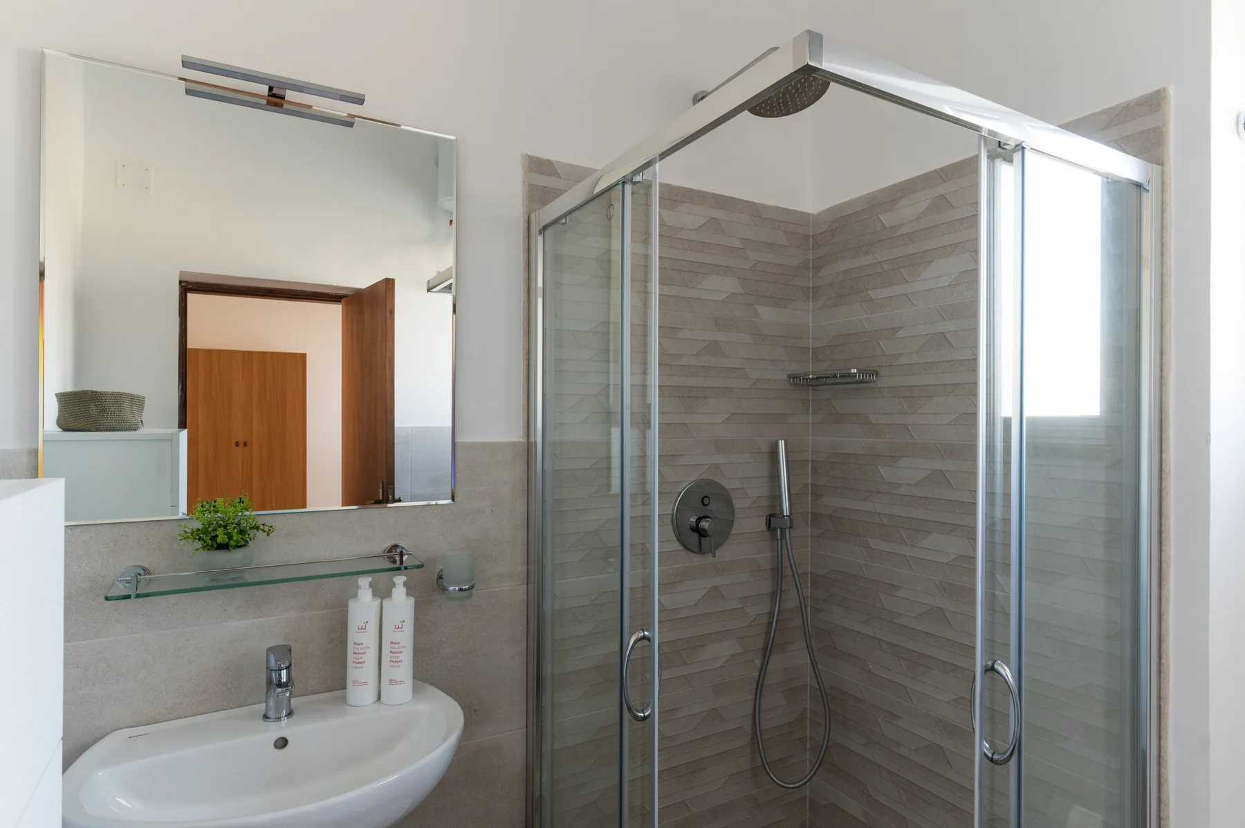 A bathroom with a sink and a glass-enclosed shower.