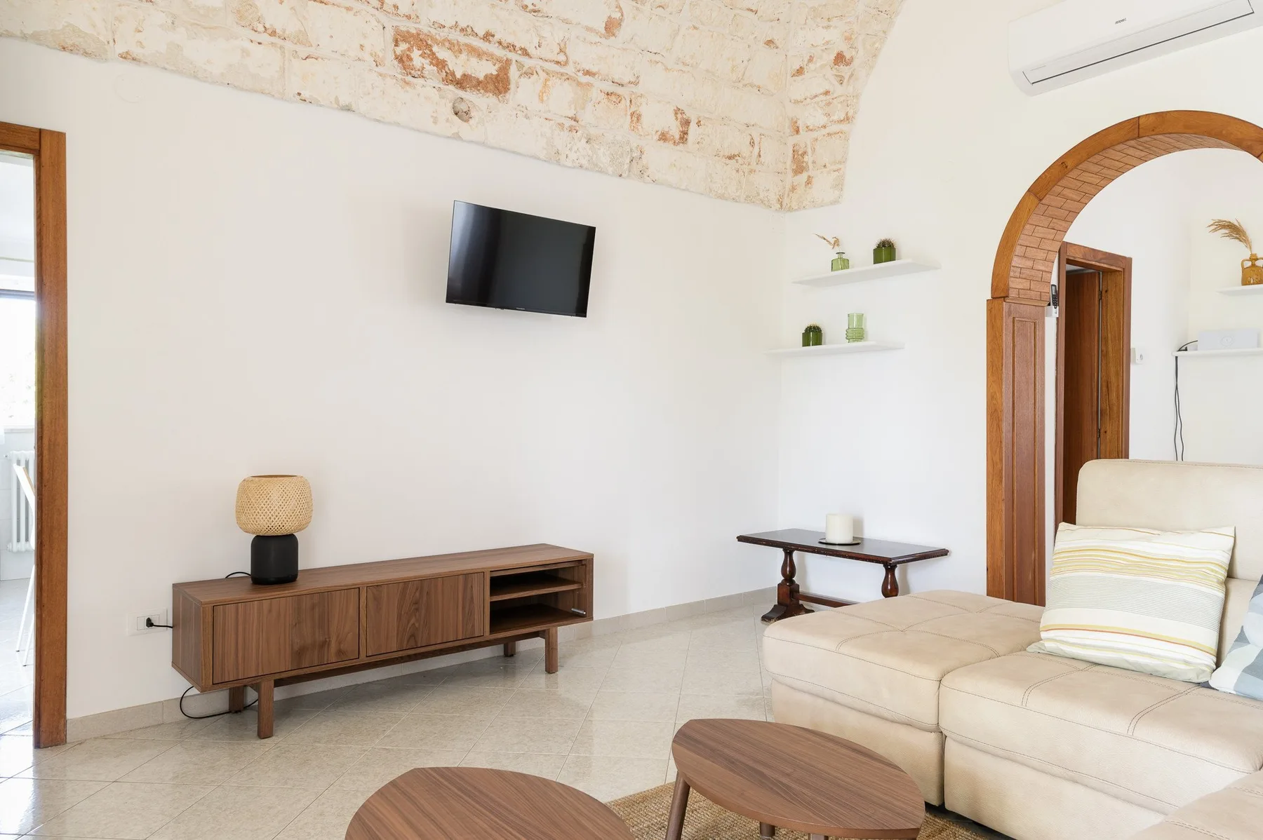A bright living room with a television, low wooden cabinet, and seating.