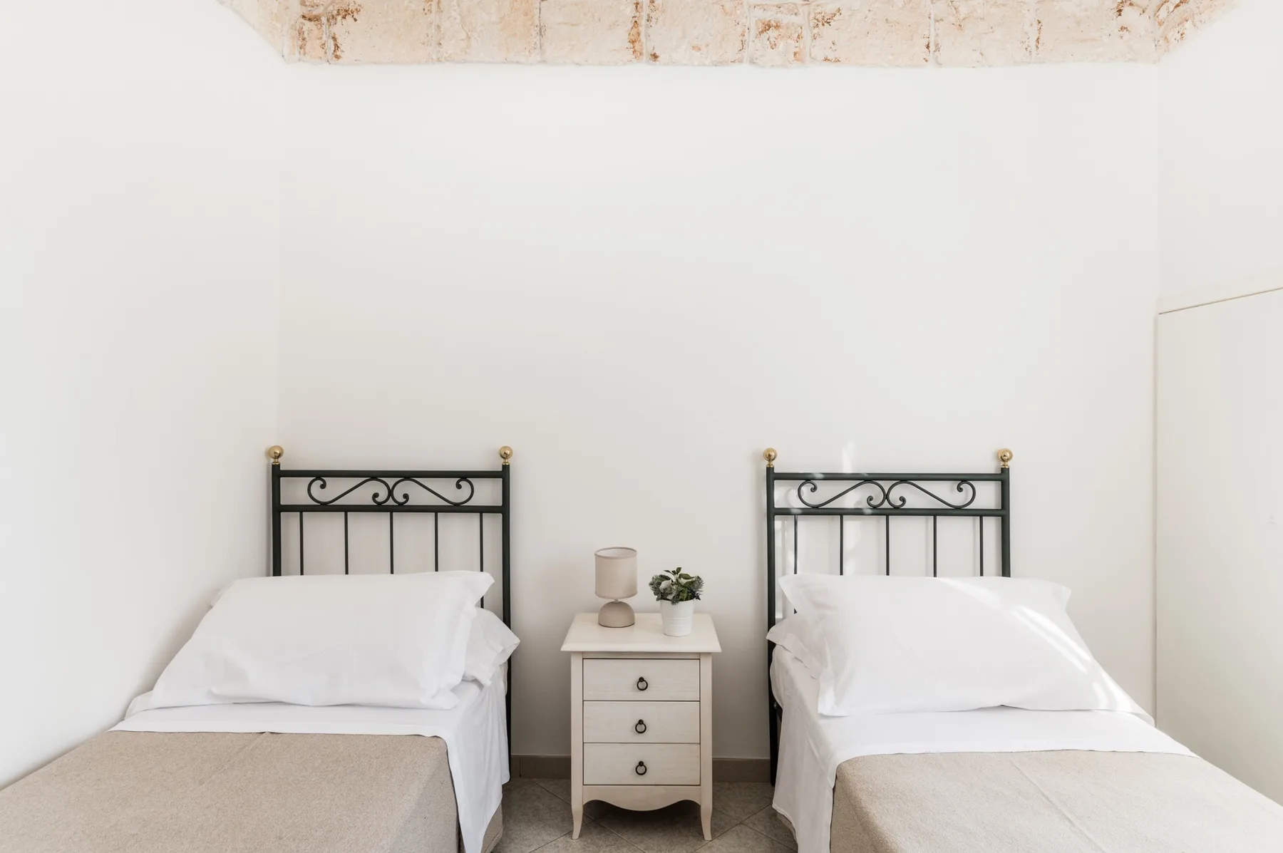 A bright bedroom with two beds and a small table between them.