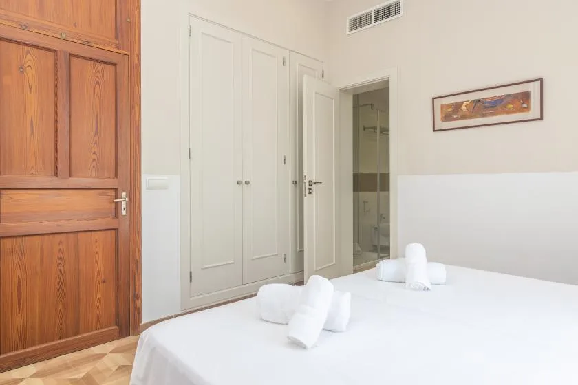Un dormitorio con una cama bien tendida y armarios empotrados.