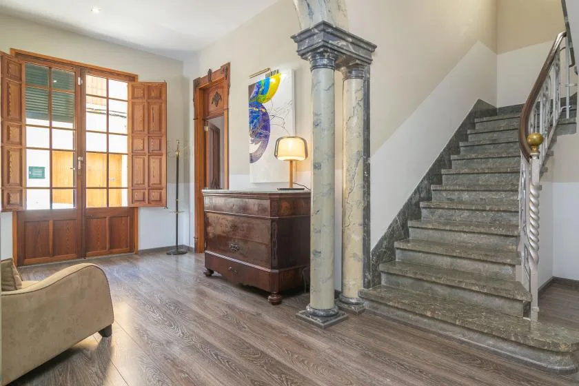 Un recibidor luminoso con un mueble de madera y una escalera.
