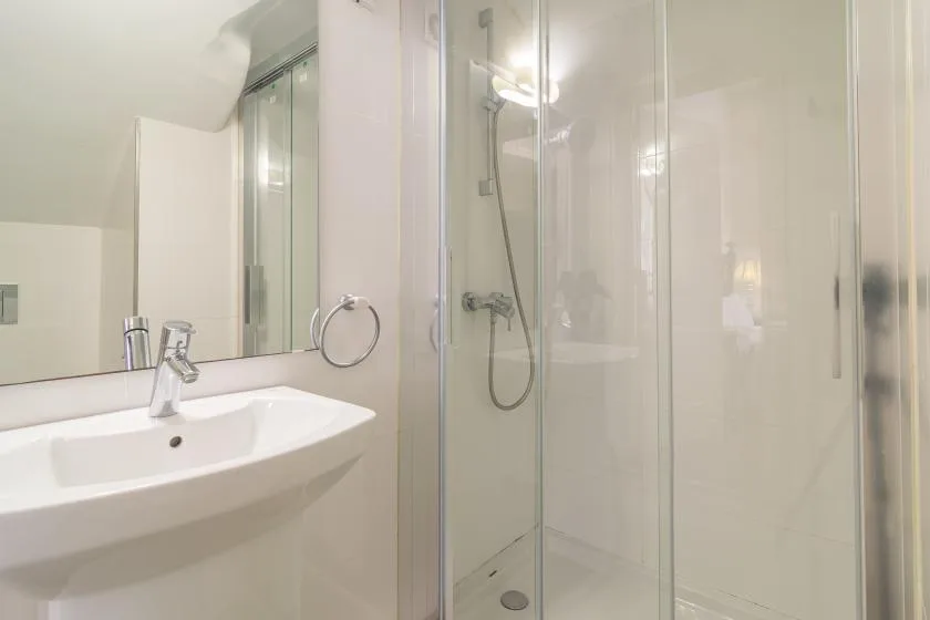 Un baño luminoso con lavabo y ducha con mampara de vidrio.