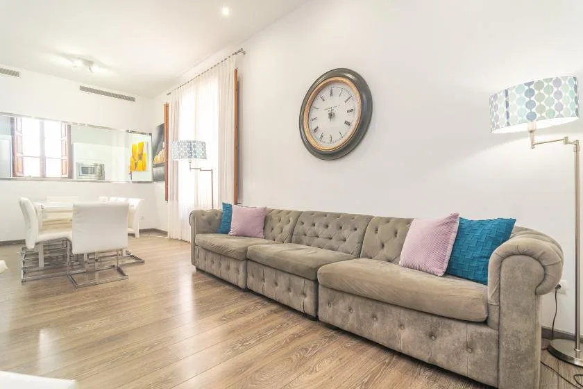 Una sala de estar y comedor con un sofá largo y una mesa de comedor.
