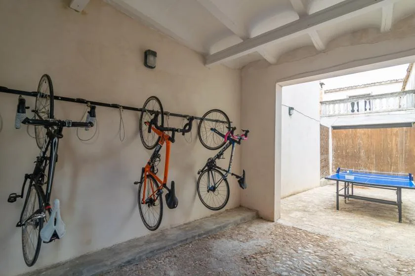 Una zona cubierta para guardar bicicletas da a un pequeño patio con una mesa de ping-pong.