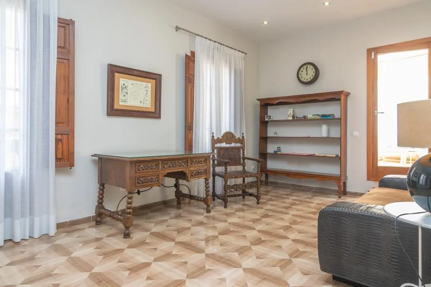 Una habitación luminosa con escritorio de madera, silla y estantería abierta.