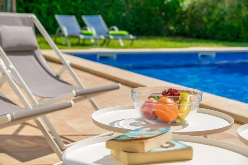 Una zona de descanso junto a la piscina, con fruta sobre una mesa pequeña.