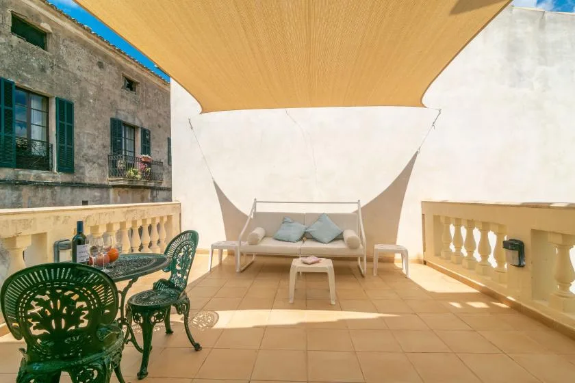Una terraza soleada con asientos al aire libre y una zona de descanso a la sombra.