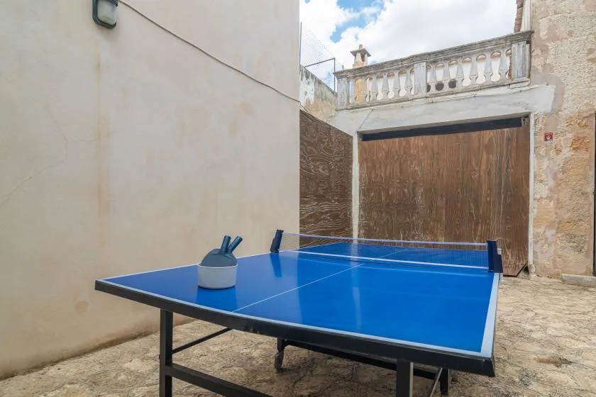 Una mesa azul de ping-pong está en un pequeño patio al aire libre.