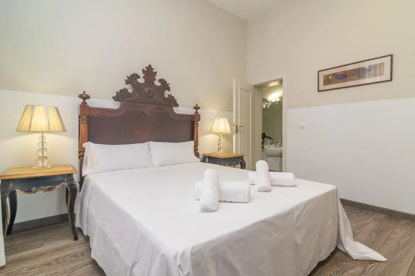 Un dormitorio con una cama bien arreglada y mesitas de noche a juego.