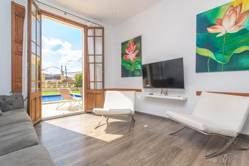 Una sala luminosa con cuadros en la pared y una puerta abierta al balcón.
