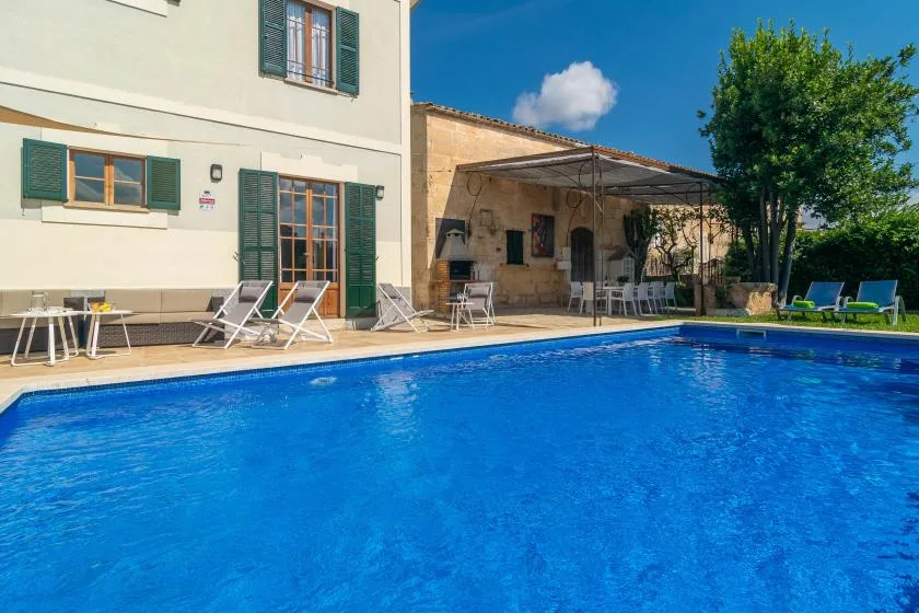 Una piscina al aire libre junto a un edificio, con asientos en el patio.