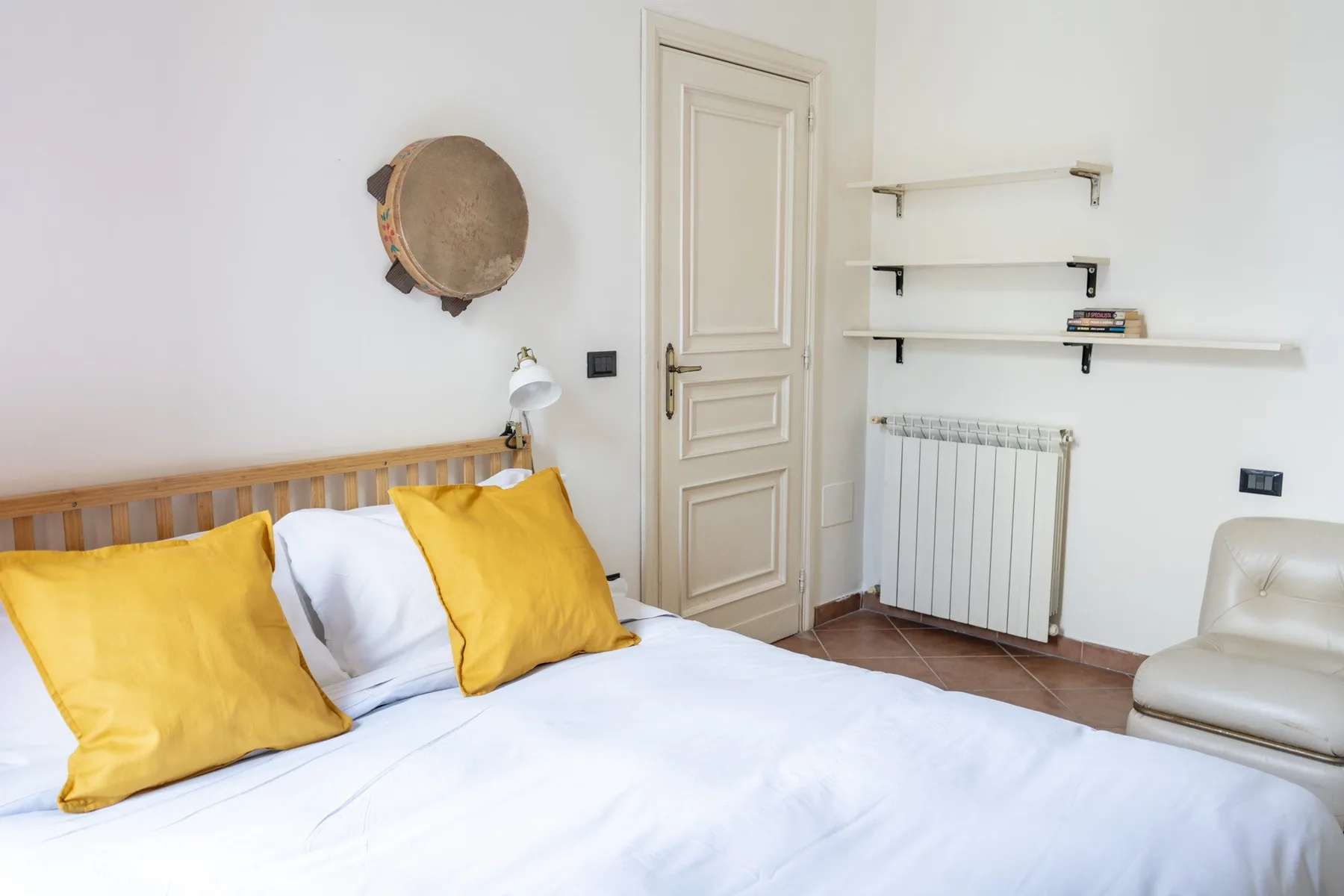 A bedroom with a neatly made bed and yellow pillows.