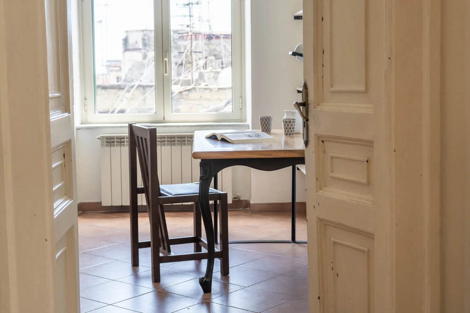 A dining area with a wooden table and chairs beside a large window.