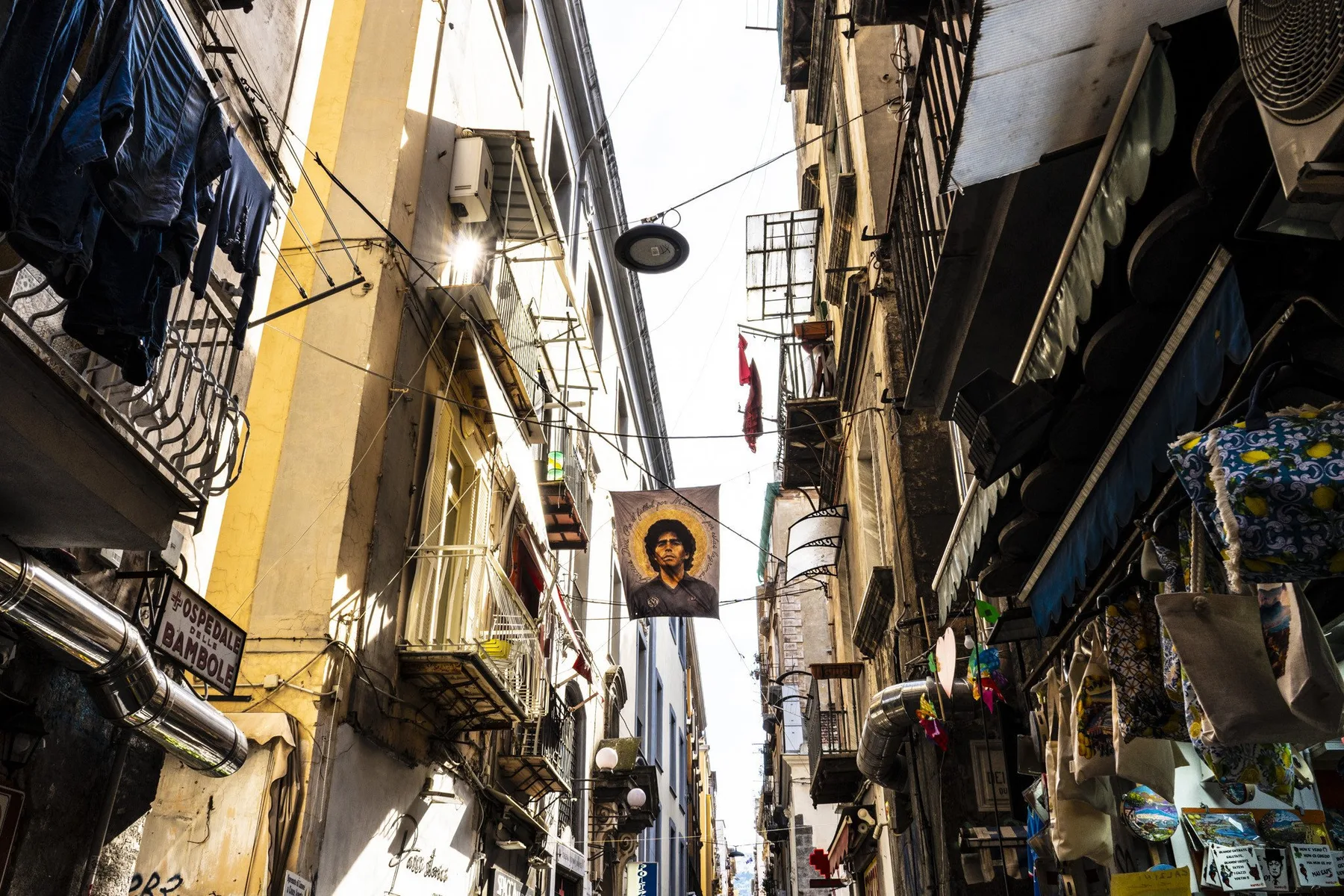 A narrow urban alley lined with closely packed buildings and hanging signs.