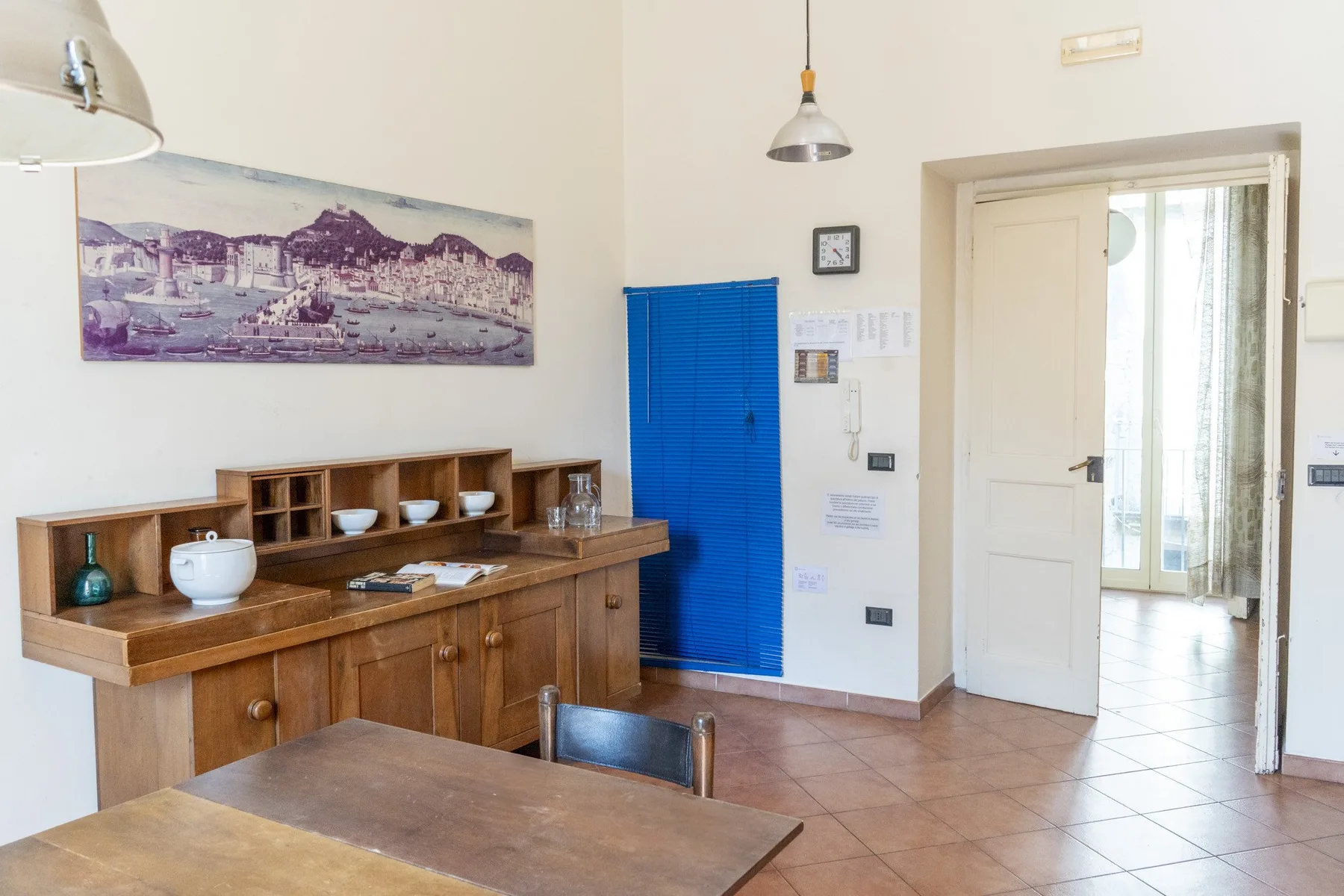 A dining area with a wooden buffet and table beside an open doorway.