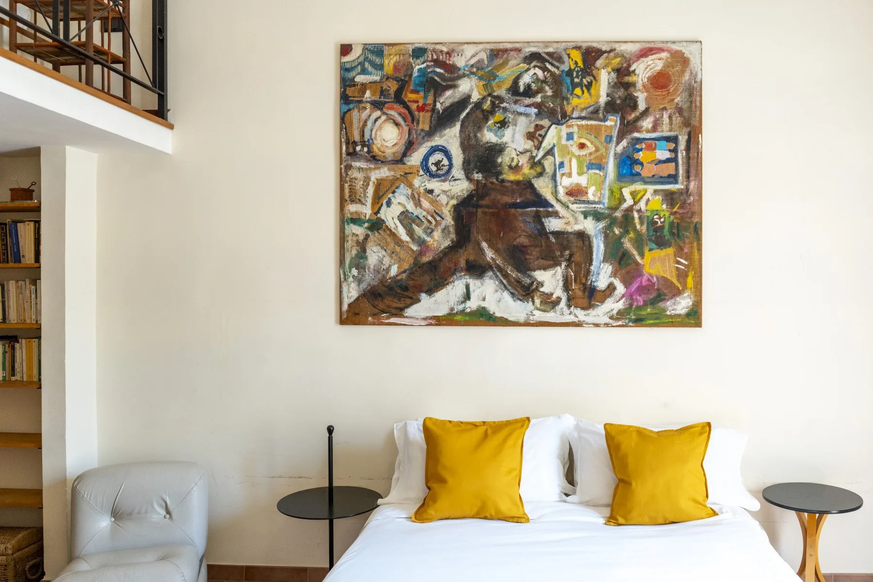 A bedroom with a bed beneath a large abstract painting.